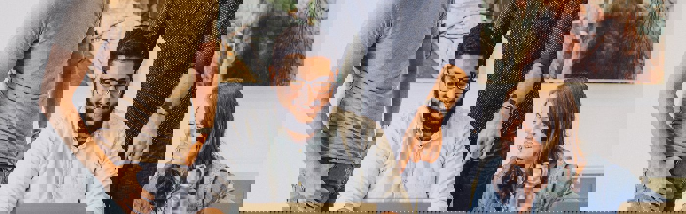 Mensen lachen achter een laptop.